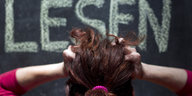 an einer Schultafel steht in groißen Buchstaben „Lesen“, eine Frau rauft sich die Haare