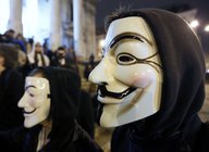 Zwei Personen im schwarzen Kapuzen-Jacken und Guy-Fawkes-Masken vor dem Gesicht