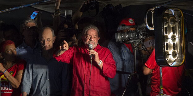 Lula da Silva spricht umringt von Anhängern in ein Mikrofon