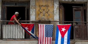 Eine Frau hängt die kubanische und die US-amerikanische Flagge an einen Balkon