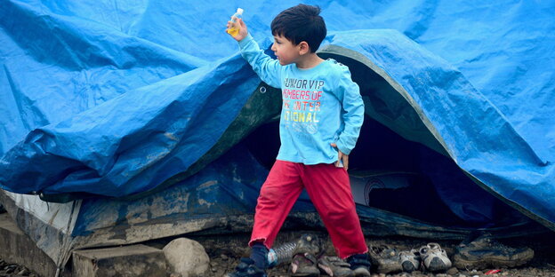 Ein Kind steht vor einer Zeltplane
