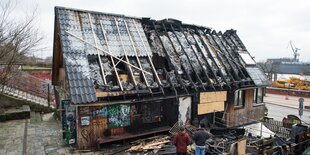 Zwei Menschen blicken auf die ausgebrannte Ruine des Pudel-Clubs.