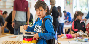 Ein siebenjähriger Flüchtling aus Afghanistan spielt eine Trommel in Deutschland-Farben.