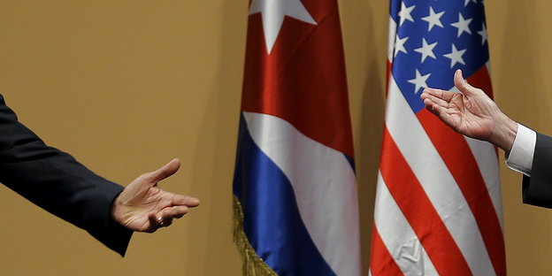 zwei ausgestreckte Hände von US- und Kuba-Fahne