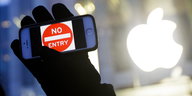 eine schwarzbehandschuhte Hand hält ein Smartphone mit einem „Einfahrt verboten“-Schild auf dem Display