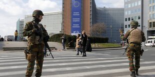 Soldaten mit Helm und Gewehren stehen auf der Straße vor einem Gebäude