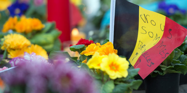 Eine belgische Flagge inmitten von Blumen, auf der Flagge steht: Wir sind Brüssel