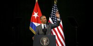 Barack Obama steht auf einer Bühne. Hinter ihm sind die kubanische und die US-amerikanische Flagge zu sehen