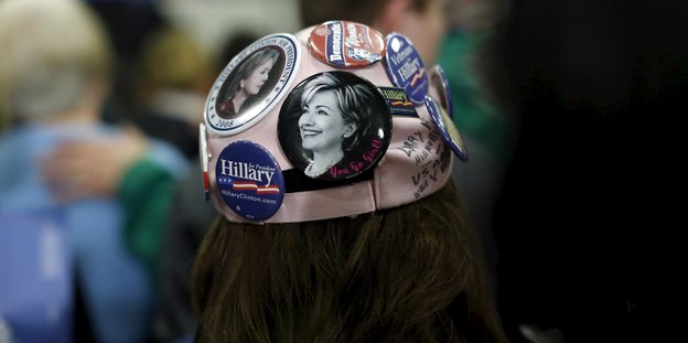 Eine Mütze mit Buttons, die das Gesicht von Hillary Clinton zeigen