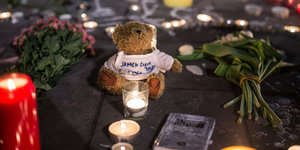 Kerzen, Blumen und ein Teddybär auf der Straße