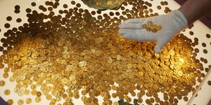 Viele alte Goldmünzen liegen auf einem Tisch