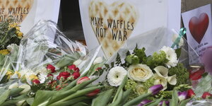 Blumen und ein Schild „Waffeln statt Krieg