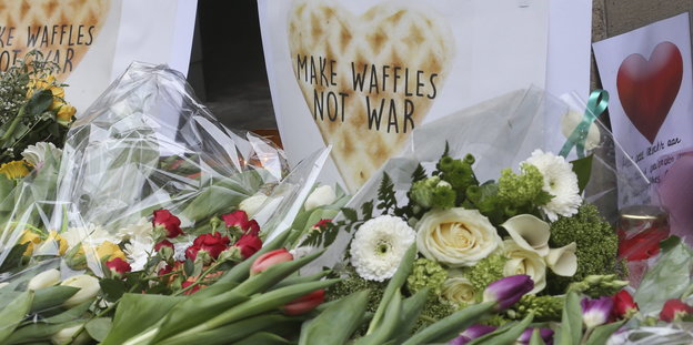 Blumen und ein Schild „Waffeln statt Krieg"