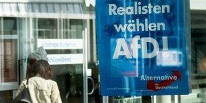 Frau neben Plakat mit Aufschrift „Realisten wählen AfD"