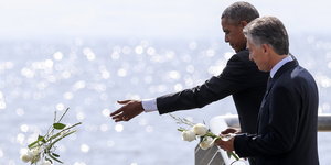 Obama und Macri werfen weiße Rosen ins Meer, von einer Mole aus.