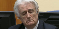 Ein Mann mit weißen Haaren, Radovan Karadžić, er hat die Augen geschlossen