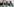 Drei Frauen sitzen hinter einem Tisch, auf dem Fotos von Kriegsopfern liegen