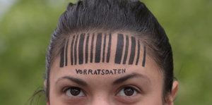 Demonstrantin gegen Vorratsdatenspeicherung mit Zeichnung eines Barcodes auf der Stirn