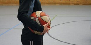 Ein Junge mit Ball in der Hand in der Turnhalle