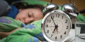 Eine Frau schläft, neben ihr ein Wecker