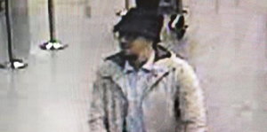 Schlecht aufgelöstes Überwachungskamerabild zeigt Mann mit Hut, Ziegenbart und Brille