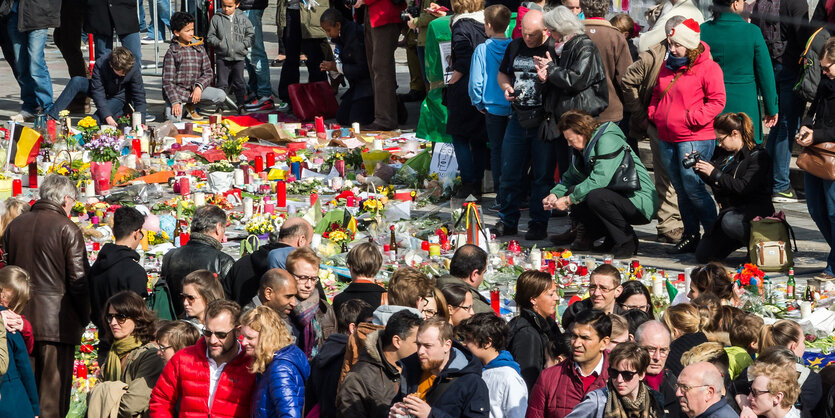 Ganz viele Menschen rund um einen Teppich aus Blumen und Kerzen