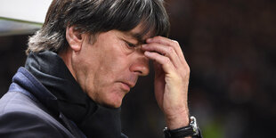 Ein Mann mit dunklen Haaren und dunklem Jacket, es ist Joachim Löw, fasst sich an die Stirn