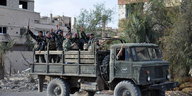 Soldaten der Armee von Assad halten auf einem Truck Waffen in die Höhe und machen das Victory-Zeichen