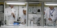 Zwei Frauen und ein Mann in weißen Kitteln arbeiten in einem Labor mit Flüssigkeiten