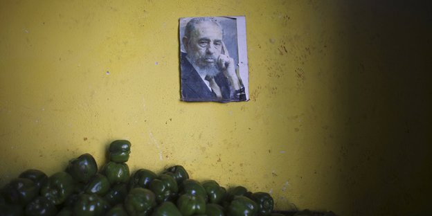 Ein Bild von Fidel Castro hängt an der Wand, am Bildrand sind grüne Paprikaschoten zu sehen