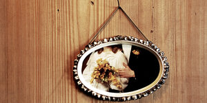 Ein Bilderrahmen mit einem Ausschnitt von einem Hochzeitspaar hängt an einer Holzwand.
