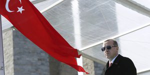 Recep Tayyip Erdogan steht mit Sonnenbrille neben der türkischen Flagge