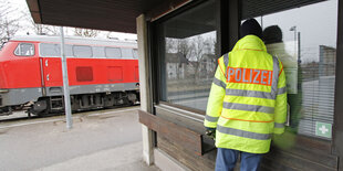 Ein Polizist steht auf einem Bahnhof