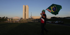 Ein Mann trägt eine brasilianische Fahne, auf der „Fora Dilma“ (Weg mit Dilma) steht