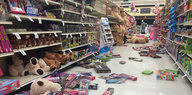 In einem Supermarkt ist Spielzeug aus den Regalen gefallen und liegt auf dem Boden verteilt herum