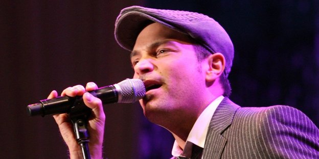 Ein Mann mit Mütze steht vor einem Mikrofon