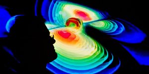 digitale Darstellung von Gravitationswellen, davor ein Mann im Profil