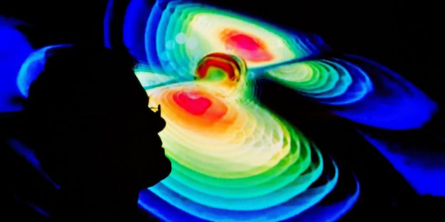 digitale Darstellung von Gravitationswellen, davor ein Mann im Profil