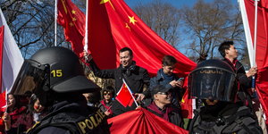 Chinesen mit roten Fahnen und Polizisten in Kampfuniformen