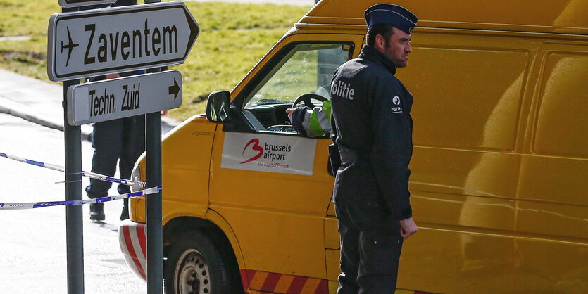 Ein Mann in Uniform steht neben einem gelben Transporter