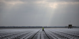 Sonnenstrahlen fallen durch graue Wolken auf ein Solarfeld in London