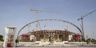 zwei Kräne, ein Bogen aus Beton, darunter Baustelle in Sonnenschein