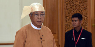 Ein Mann, es ist Htin Kyaw, blickt mit traditioneller Kopfbekleidung, in die Kamera