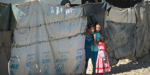 Kinder vor einer Zeltplane des UNHCR
