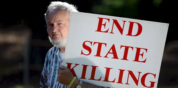 Ein Mann hält ein Schild, auf dem „End State Killing“ steht
