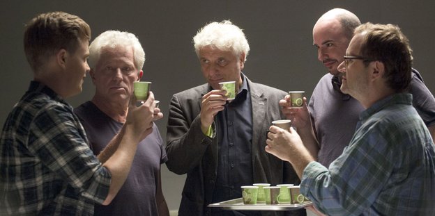 Fünf Männer trinken aus kleinen Bechern