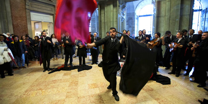 Ein Mann wirbelt mit Fahnen, dazu spielt ein Orchester
