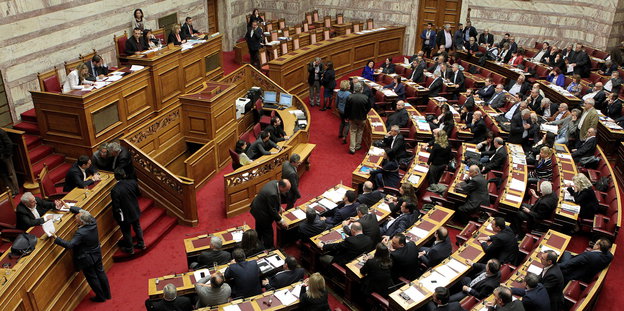 Menschen sitzen in einem Saal. Es ist das griechische Parlament.