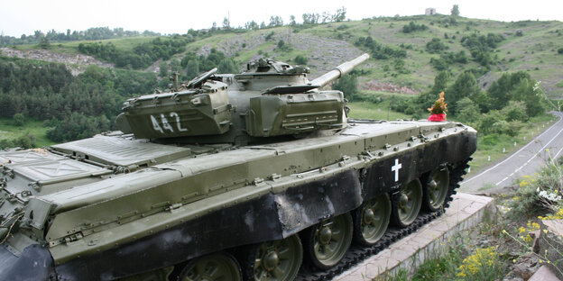 Ein Panzer vor grünen Hügeln