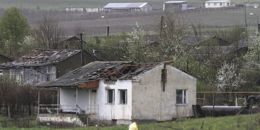 Ein Haus mit einem Dachschaden steht auf einer grünen Wiese